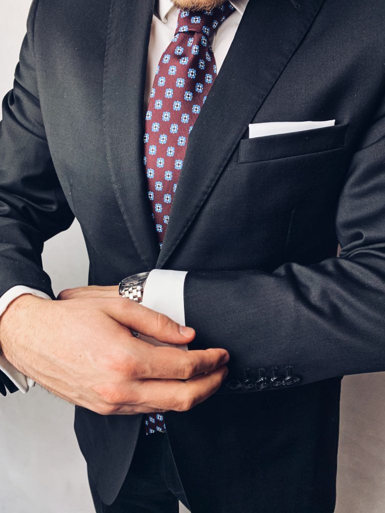 Czarny garnitur z dodatkami: bordowy jedwabny krawat oraz biała poszetka. Jak ubrać się na wesele?